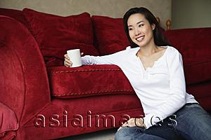Asia Images Group - woman sitting on floor holding coffee cup