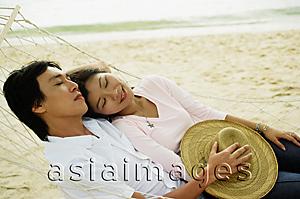 Asia Images Group - Couple lying in hammock on beach, eyes closed