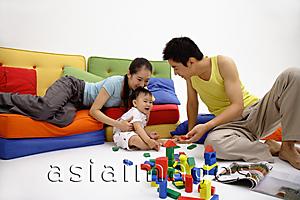 Asia Images Group - Family with one child, sitting in living room, playing with wooden toy blocks