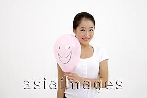 Asia Images Group - Woman holding pink balloon with smiley face drawn on it