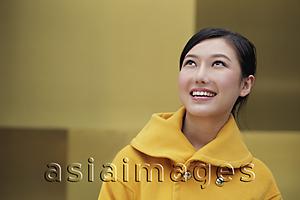 Asia Images Group - Young woman in yellow coat looking up