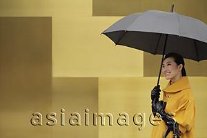 Asia Images Group - Young woman wearing a coat and gloves holding an umbrella