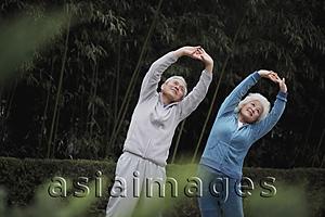 Asia Images Group - Older man and woman stretching together outdoors