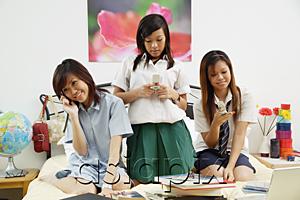 AsiaPix - Girls in school uniform sitting on bed, using mobile phones