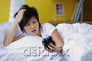 AsiaPix - Woman in bed, looking at alarm clock