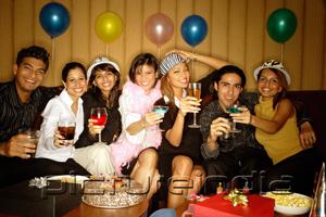 PictureIndia - Young adults sitting side by side, celebrating, holding drinks