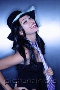 PictureIndia - Young woman, wearing hat and tie, smiling, looking at camera