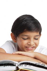 PictureIndia - Boy leaning head on hand, looking at book