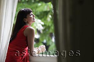 Asia Images Group - Indian woman looking out window, smiling