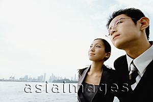 Asia Images Group - Male and female executive looking up, blue sky in background, portrait