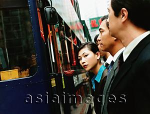 Asia Images Group - Executives waiting for bus, female executive looking at camera.
