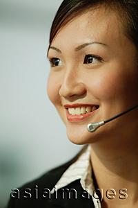 Asia Images Group - Young woman wearing hands-free device, looking away, smiling