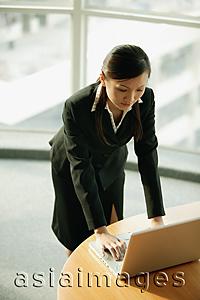 Asia Images Group - Young woman standing, using laptop