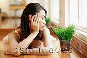 Asia Images Group - Young woman, hands on head, looking at plant