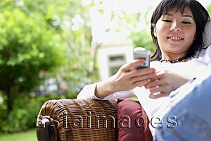 Asia Images Group - Woman using mobile phone, text messaging, smiling