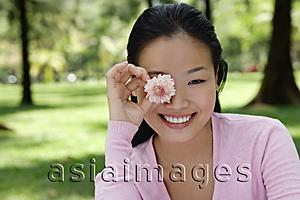 Asia Images Group - Young woman holding flower over eye