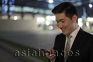 Asia Images Group - Man wearing a business suit, smiling at phone at night