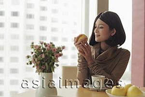 Asia Images Group - Young woman looking at apple and smiling