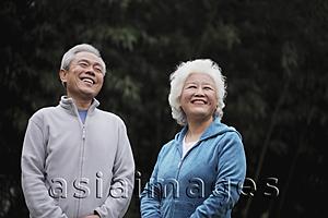 Asia Images Group - A senior couple in sweatsuits laughing outdoors