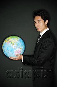 AsiaPix - Businessman holding globe in hands, looking at camera