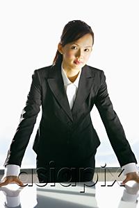 AsiaPix - Businesswoman leaning on table, looking at camera