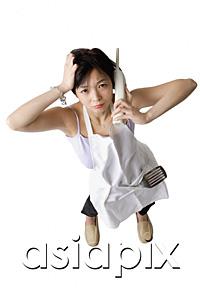 AsiaPix - Woman in apron using cordless phone, frowning