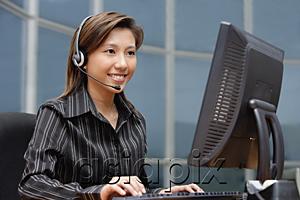 AsiaPix - Businesswoman with hands free device, using computer