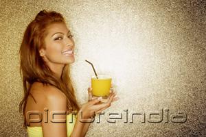 PictureIndia - Young woman holding drink, looking at camera, portrait