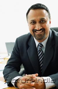PictureIndia - Businessman at desk, looking at camera, smiling